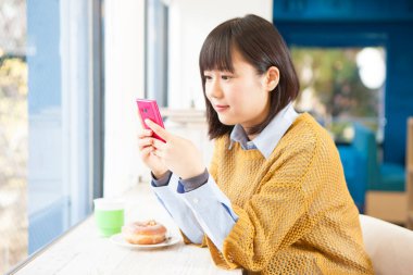 Kafede akıllı telefonlu güzel Asyalı kadının portresi.