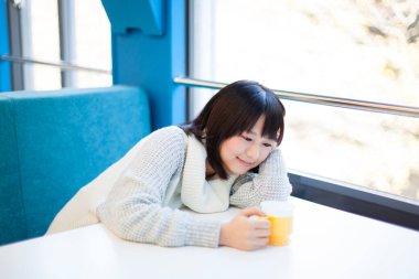 Bir fincan kahveyle güzel bir Asyalı kadının yakın plan portresi.