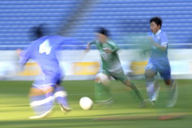 Genç Japon erkekler stadyumda futbol oynuyor, spor geçmişi bulanık insanlarla dolu. 