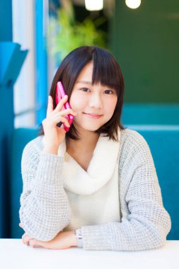 Akıllı telefonlu güzel Asyalı bir kadının yakın plan portresi.