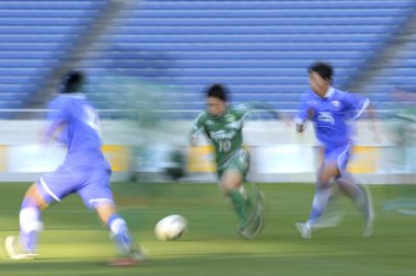 Genç Japon erkekler stadyumda futbol oynuyor, spor geçmişi bulanık insanlarla dolu. 
