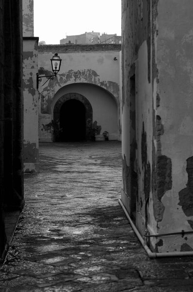 Narrow cobblestone alley leading toward old arched doorway