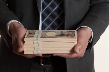 Japon parası, yeni banknotlar tutan bir adamın elleri.