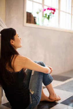 Kadın pencerenin kenarında oturuyor.