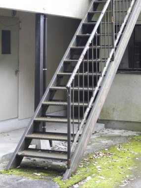 Binanın dışındaki yosunlu paslı metal merdiven.