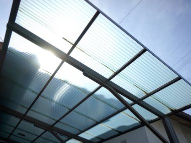 Gündüz vakti şeffaf çatı panellerinden güneş ışığı yansıyor.