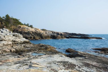 Sahildeki kayalık deniz manzarası, deniz dalgaları ve kayalar.   