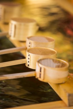 Bambu su kepçeleri suyun yanındaki ahşap platformda dinleniyor.