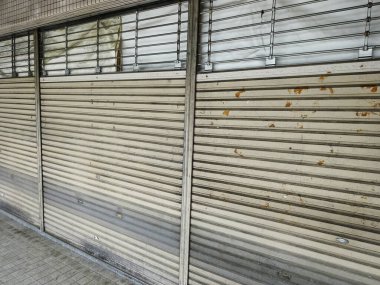 Eskimiş metal kepenkler mağaza pencerelerini gün boyunca kapatıyor