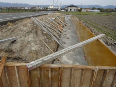 Kırsal yol ve tarlaların yanında inşaat halindeki beton drenaj hendeği