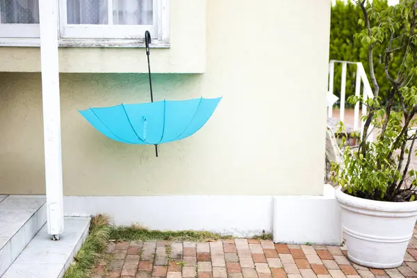 blue umbrella hanging on the window of the house