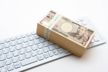 Beyaz arka planda klavyesi olan Japon Yen parası.