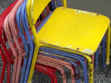 Kirli renkli sandalyeler bir sokakta yığılıyor.