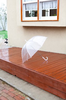 Islak tahta güvertede yağmurdan sonra beyaz şemsiye