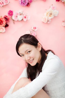 Pembe duvarın önünde çiçekli güzel Asyalı bir kadının portresi.