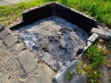 Etrafı taşlarla ve otlarla çevrili boş ateş çukuru.