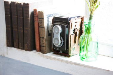 Pencerenin yanındaki eski kitapların yanında dinlenen klasik kamera