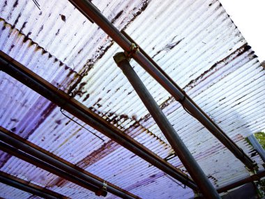 Paslı metal borular eski çatılı paneller boyunca akıyor.