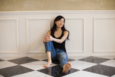 Genç, güzel Çinli kadın oturma odasında yerde oturuyor.