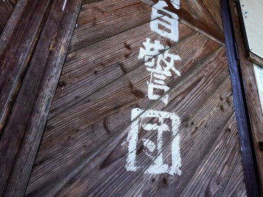 Soluk beyaz karakterler ve dokulardan oluşan eskimiş ahşap bir kapı.