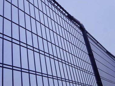 Açık mavi gökyüzüne doğru uzanan uzun metal çitler.