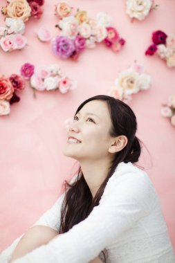 Pembe duvarın önünde çiçekli güzel Asyalı bir kadının portresi.