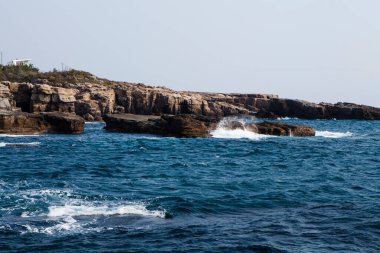 Sahildeki kayalık deniz manzarası, deniz dalgaları ve kayalar.   