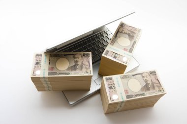  Arka planda bir yığın Japon Yen parası ve dizüstü bilgisayar