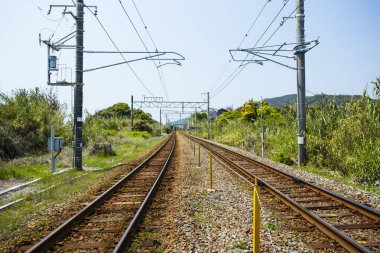 Güneşli bir gün uzak tepelere uzanan demiryolu raylarını gösteriyor