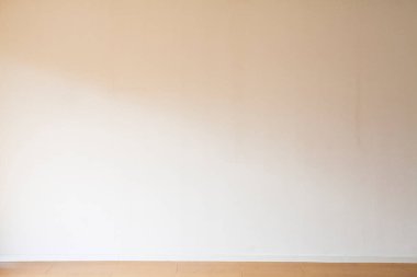 Ahşap zemini ve beyaz duvarı olan boş bir oda. 