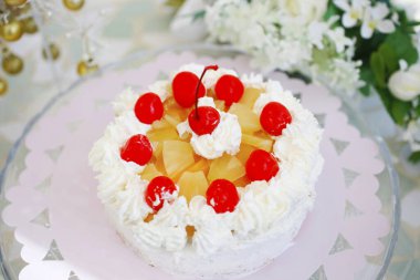 Üstünde kirazlar olan çilekli sütlü kek.