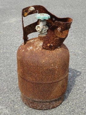 Sert kaldırım yüzeyinde duran paslı metal gaz silindiri