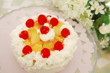 Üstünde kirazlar olan çilekli sütlü kek.