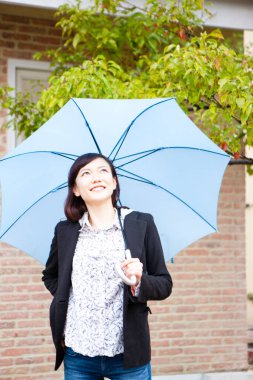 Dışarıda, yağmurun altında şemsiyeli güzel Asyalı bir kadının portresi.