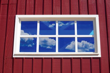 Mavi gökyüzü yansımalı kırmızı ahşap duvar ve pencere