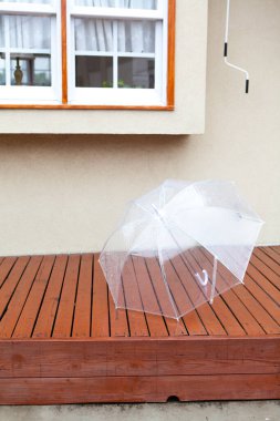 Yağmurdan sonra bahçedeki ahşap güvertede şemsiye