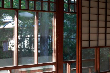 Japonların arka planında Japon bahçesi ve penceresi var.