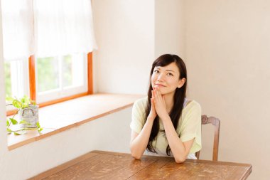 Asyalı kadın mutfakta masada oturuyor. 