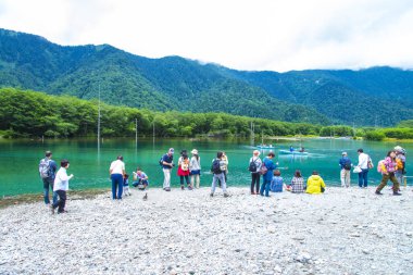 Dağ gölünün yanında duran bir grup insan.