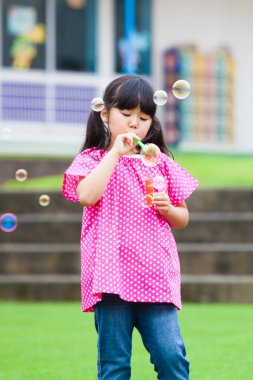 Puantiyeli tişörtle baloncuk çıkaran kız.