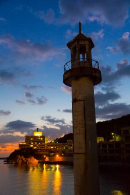 Deniz feneri doğanın arka planında gün batımında