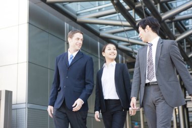 Ofis binasının önünde yürüyen genç iş adamları