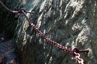 Rusty chain attached to rock surface in natural setting