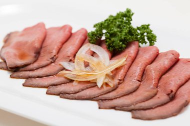 Beyaz tabakta çiğ domuz resmi.