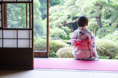 Japonların kimono giymiş arka planda oturan ve bahçeye bakan kadınlar.