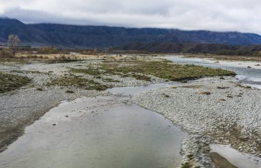 Karlı bir vadinin ortasındaki dağ nehrinin dikey görüntüsü.