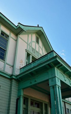 Şehirde gündüz vakti terk edilmiş yeşil bir bina. 