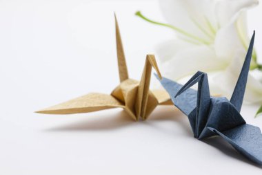 Beyaz arka planda güzel zambak çiçeği ve origami turnalarının yakın plan görüntüsü                   