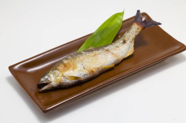 Tabağında yeşil yaprak olan lezzetli ızgara balığın yakın plan görüntüsü     