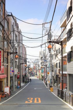 Boş cadde binalar ve elektrik hatlarıyla dolu.